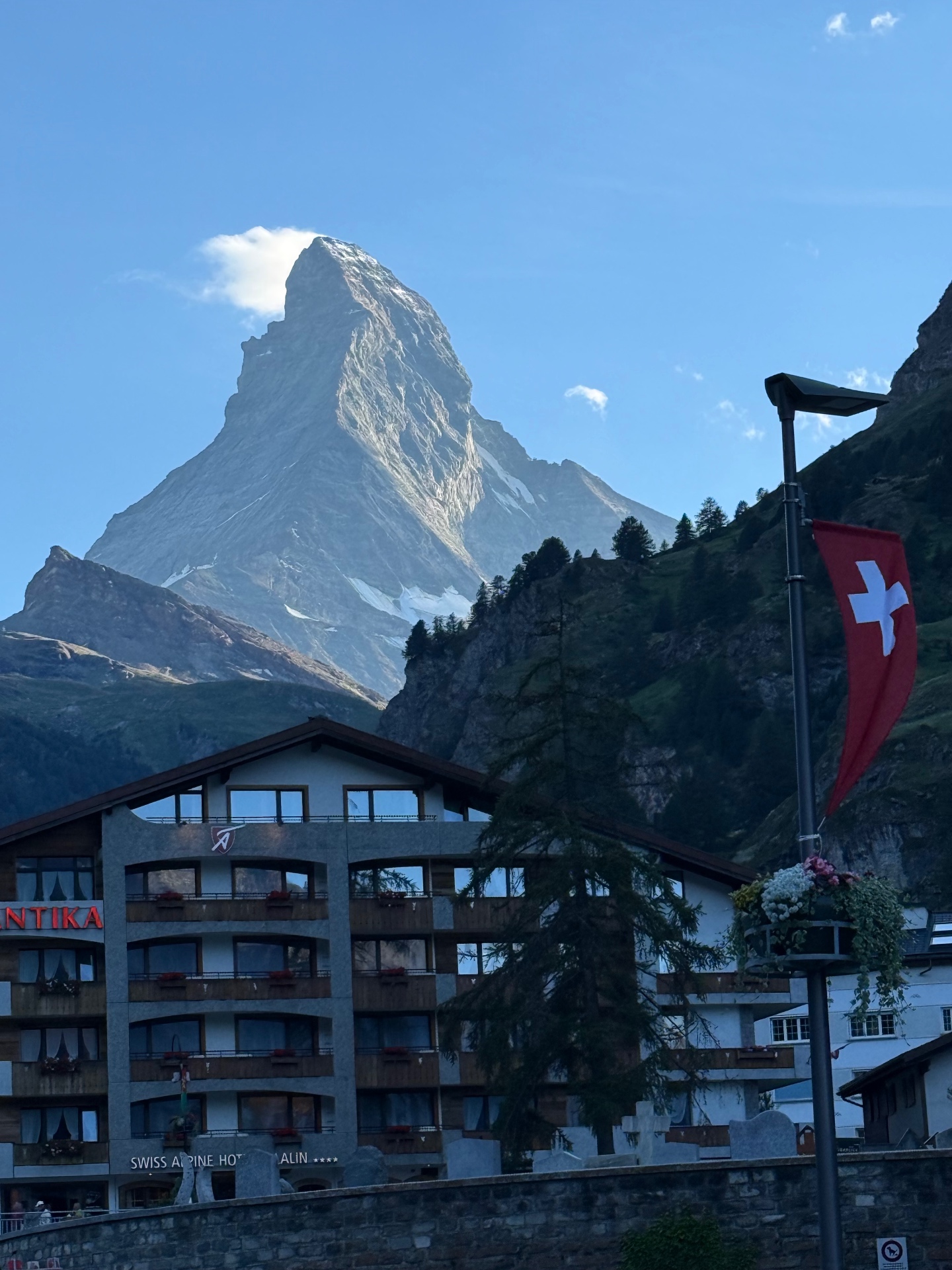 The Matterhorn rising above a Zermatt hotel and a Swiss flag on a lamppost